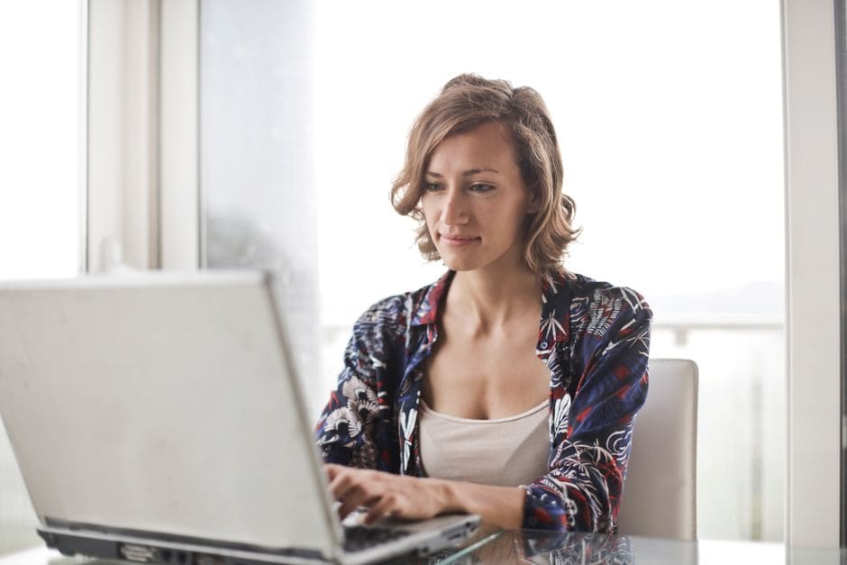 A woman working on a laptop at a sunlit desk in summer